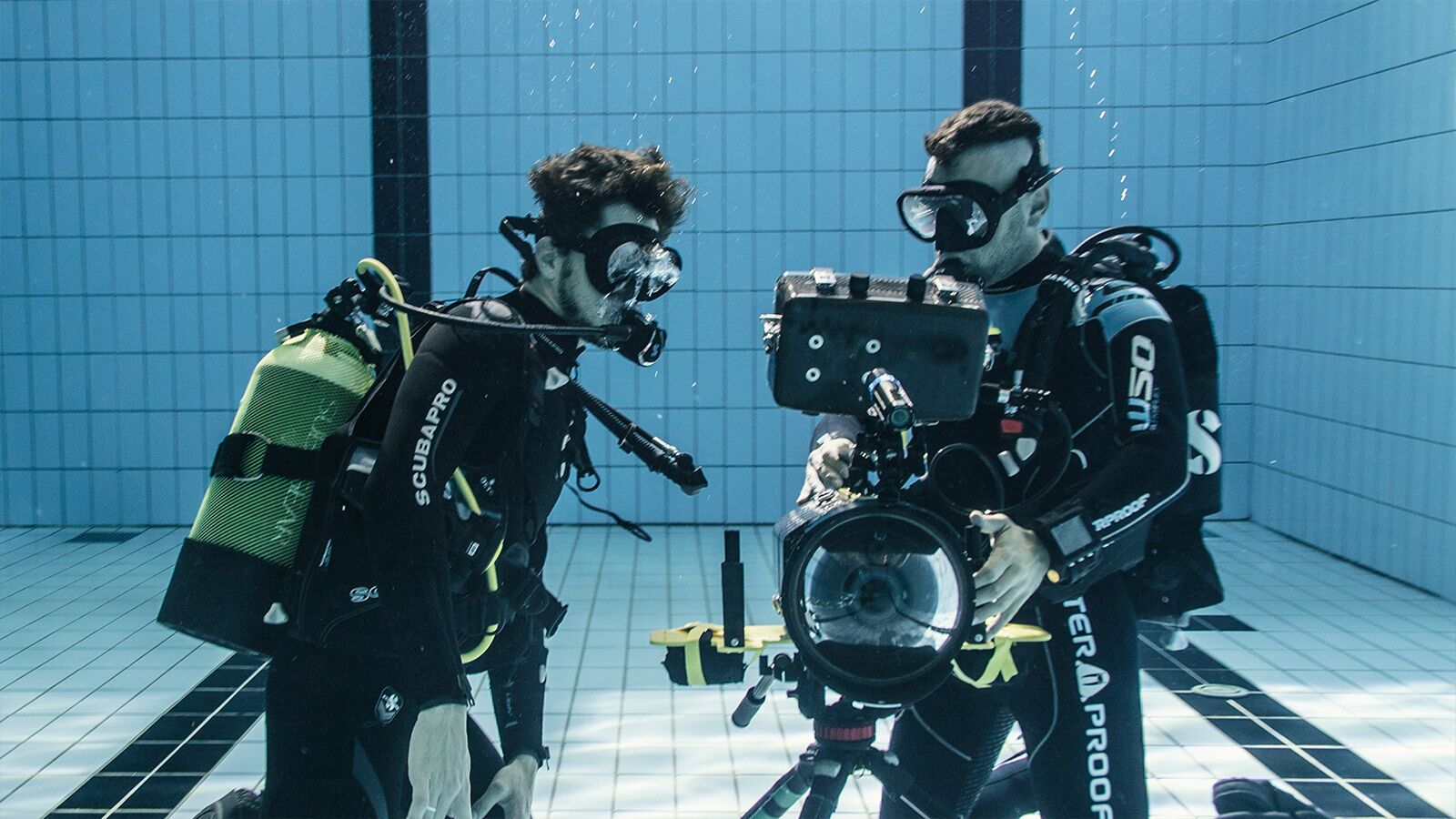 Two scuba divers in a pool with cameras